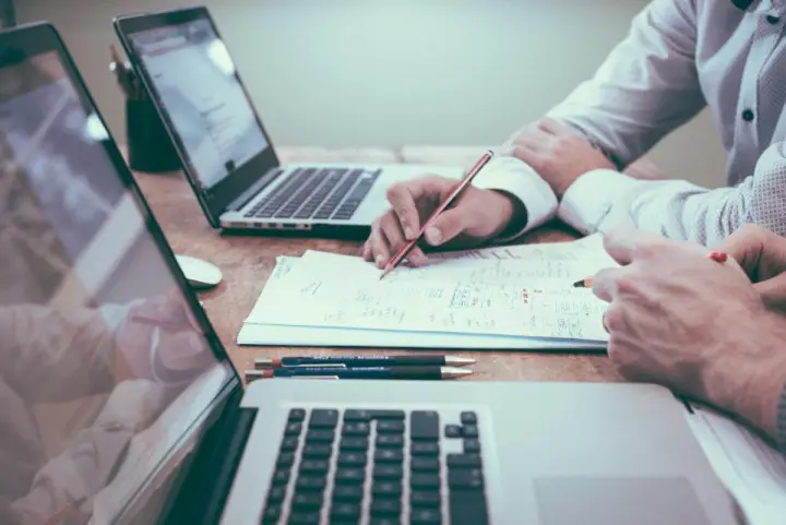 Personas trabajando con computadoras y reportes
